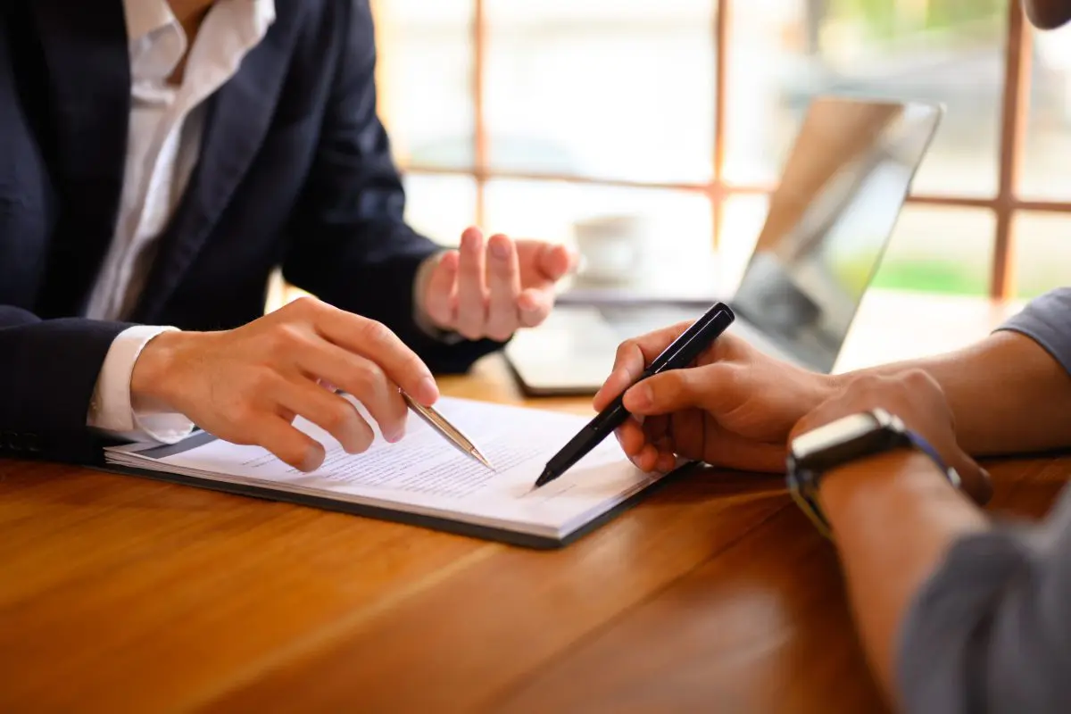 Two people are sitting at a table and one is holding a pen